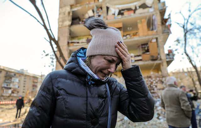 A woman cries outside an apartment building destroyed by Russian shelling.