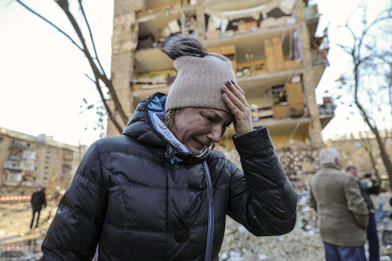 A woman cries outside an apartment building destroyed by Russian shelling.