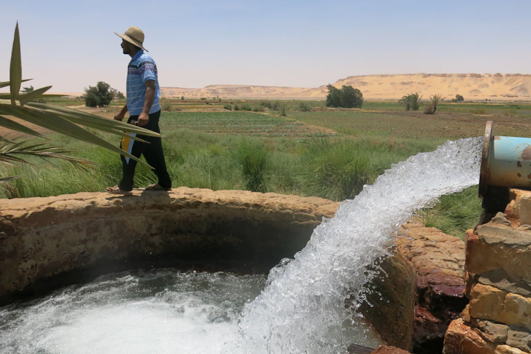 Water rushing from pipe, fields in background
