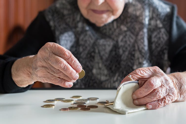 An elderly woman counts coins from a small purse