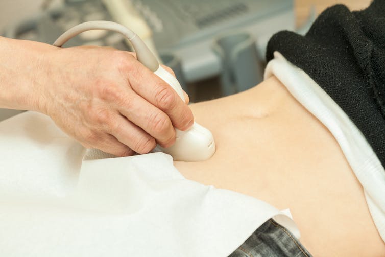 Close-up of person receiving abdominal ultrasound exam.