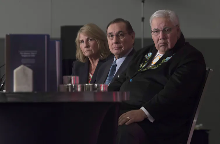 Three people seen sitting at a table.