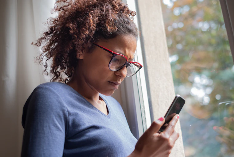 A woman looks at her phone, appears unsettled.