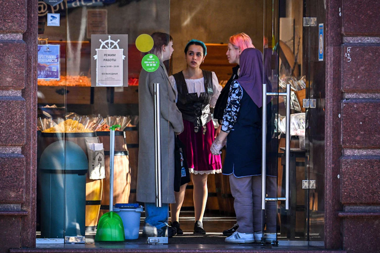 Three people talk inside a shop
