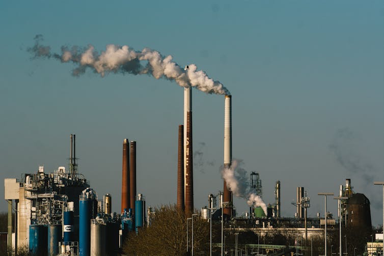 An industrial plant has smokestacks steaming into the sky