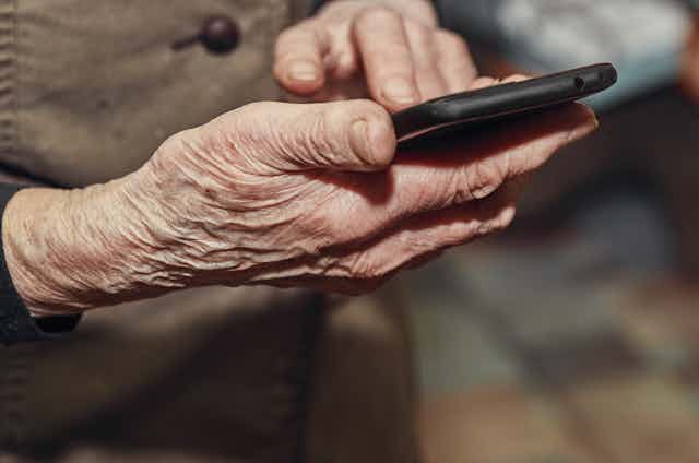an elderly pair of hands holds a smartphone