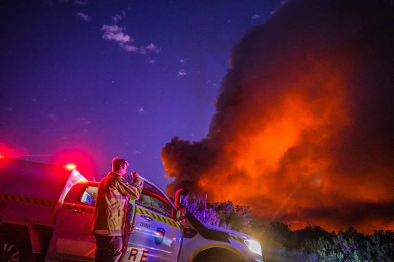 fire official watches orange smoke plume