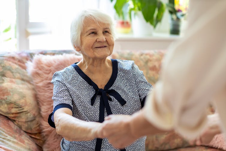 Older woman holding hands with young person