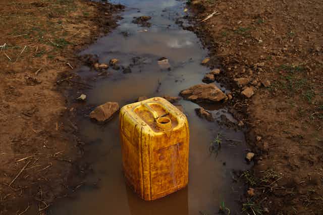 A yellow jerrycan sits in a dirty river