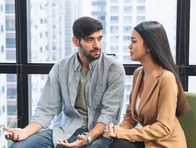 A heterosexual couple sitting next to each other are having a serious discussion.