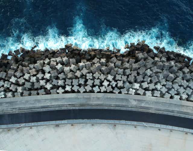 A coastal barrier made up of concrete blocks seen from above.