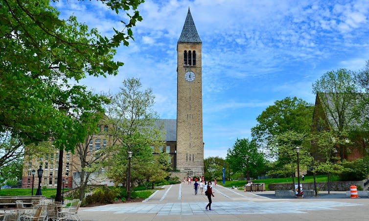 A tower is seen on a university campus as students walk by.