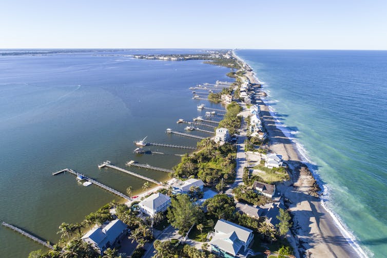 Homes along a narrow barrier island with docks out into the bay side.