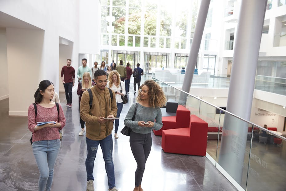 Students are seen walking in a university hallway.