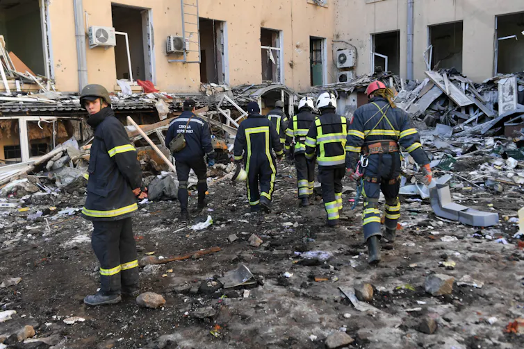 Emergency services workers searching through rubble.