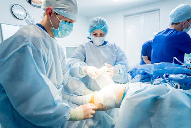 Surgeons wrap a leg in bandage in the operating room. 