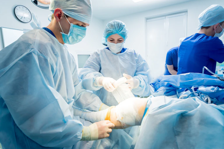 Surgeons wrap a leg in bandage in the operating room.
