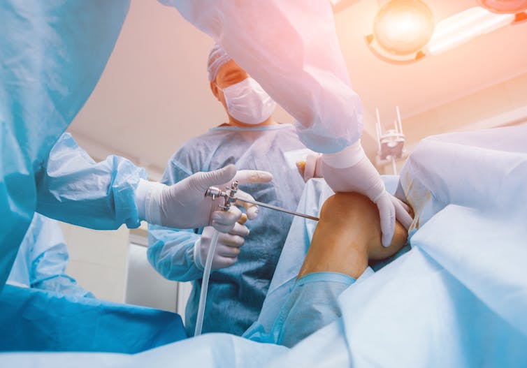 Surgeon drills into a knee in operating theatre