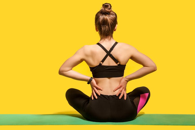 Fit woman in exercise wear clutching sore lower back