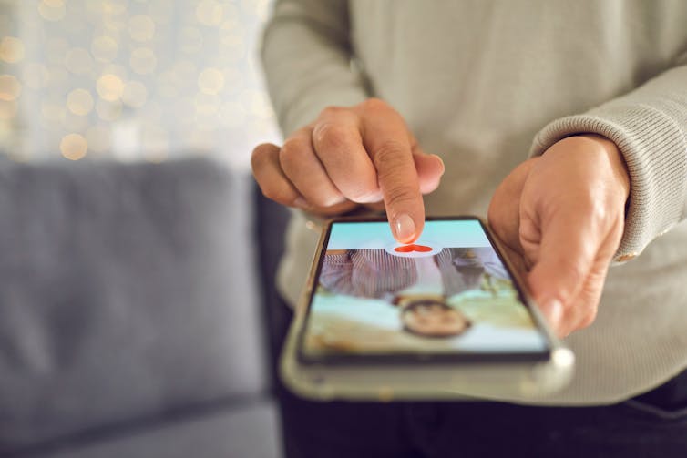 Hands holding a smartphone, which is displaying a dating app.