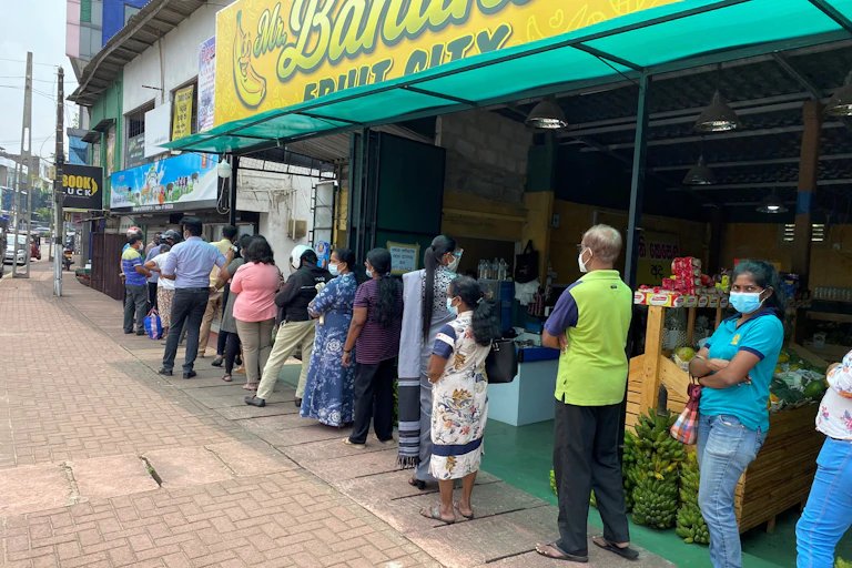 A queue of people wait for the chance to buy milk.