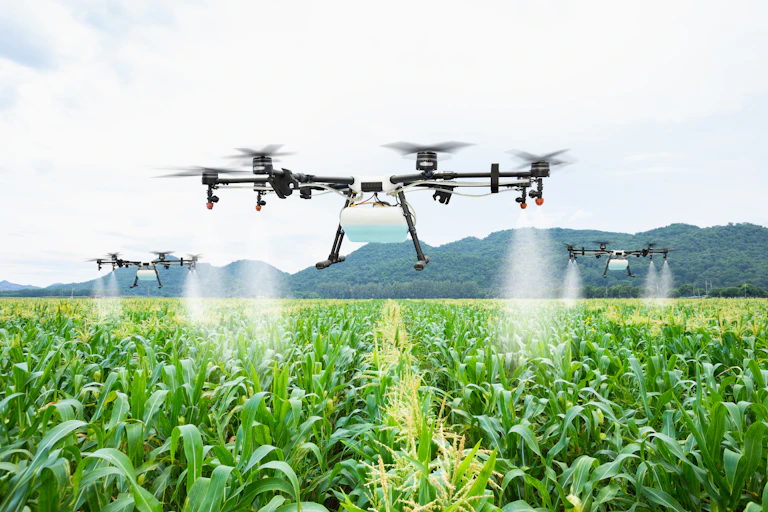 Drones flying over a field of crops.