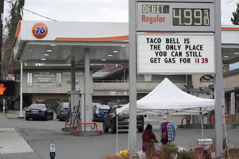 Signboard with a joke about gasoline prices below a curent price of $4.99 per gallon for regular