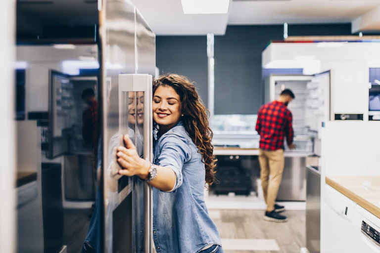 a woman hugs a refrigerator in a kitchen