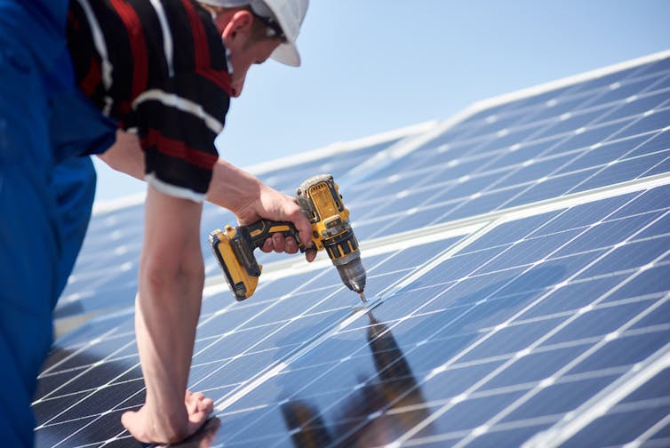 Worker attaching a solar panel to a house