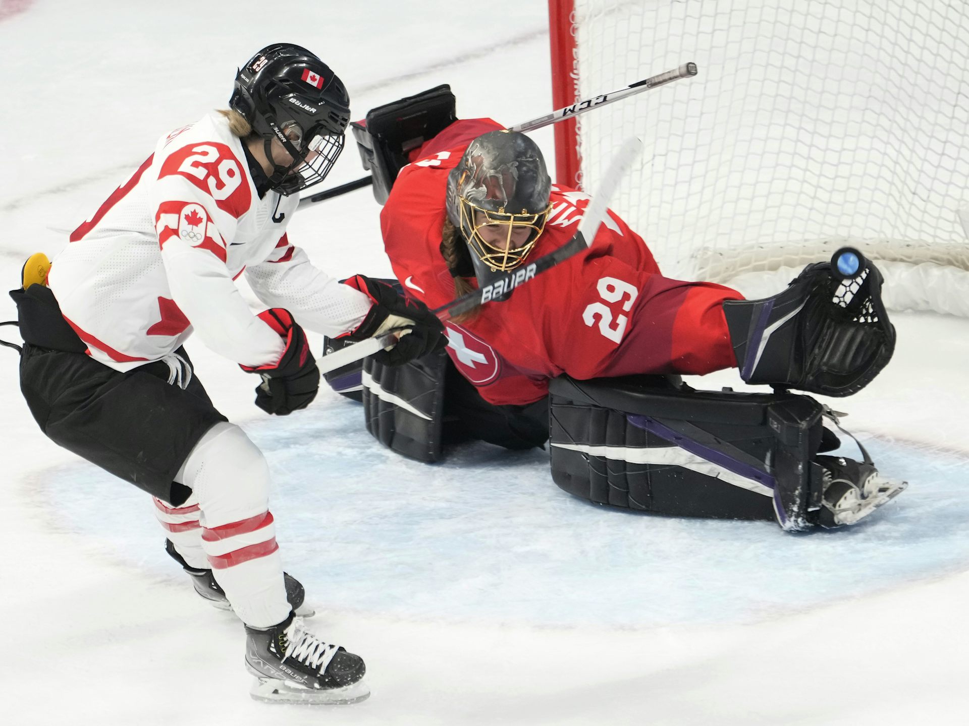 A hockey player scoring a goal on a hockey goalie