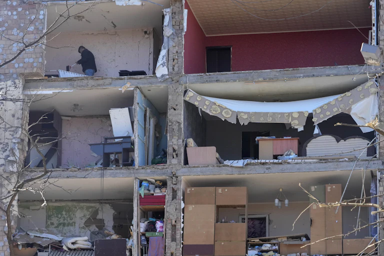 A man is seen sweeping his decimated apartment.