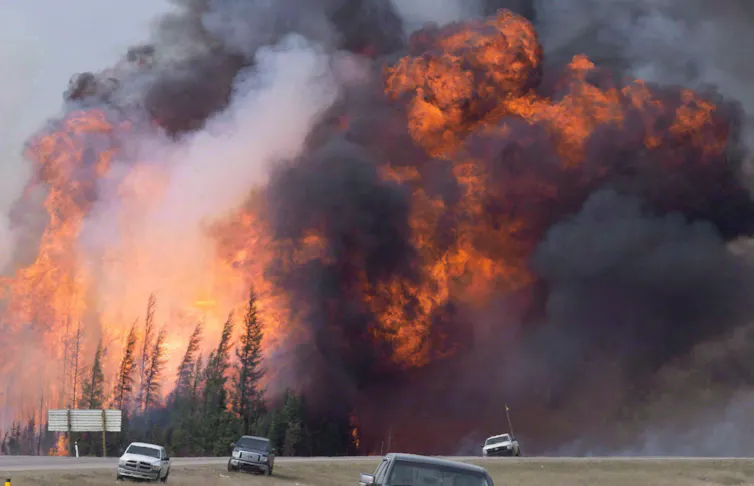 A giant fireball is seen behind cars on a highway.