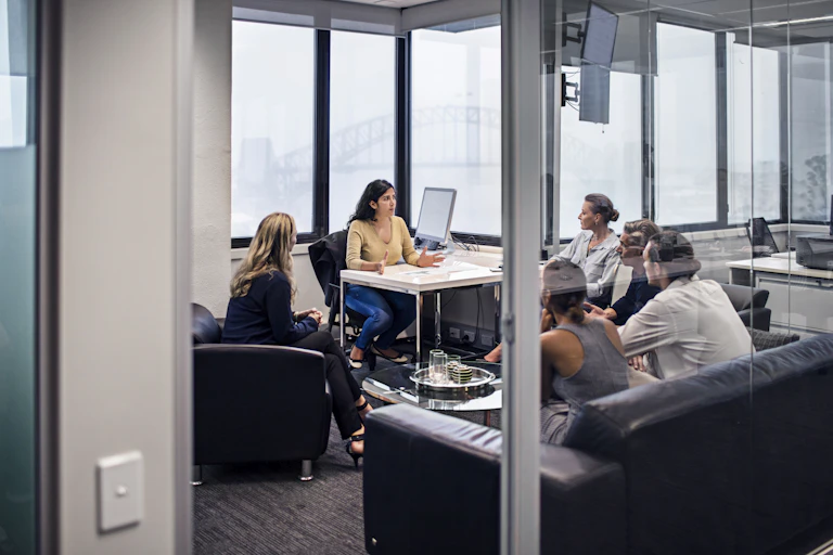 A group of people sit in an office having a discussion.