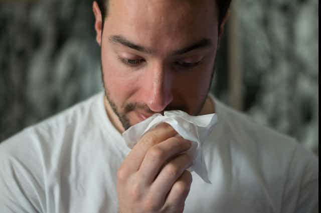 Man puts tissue to his nose