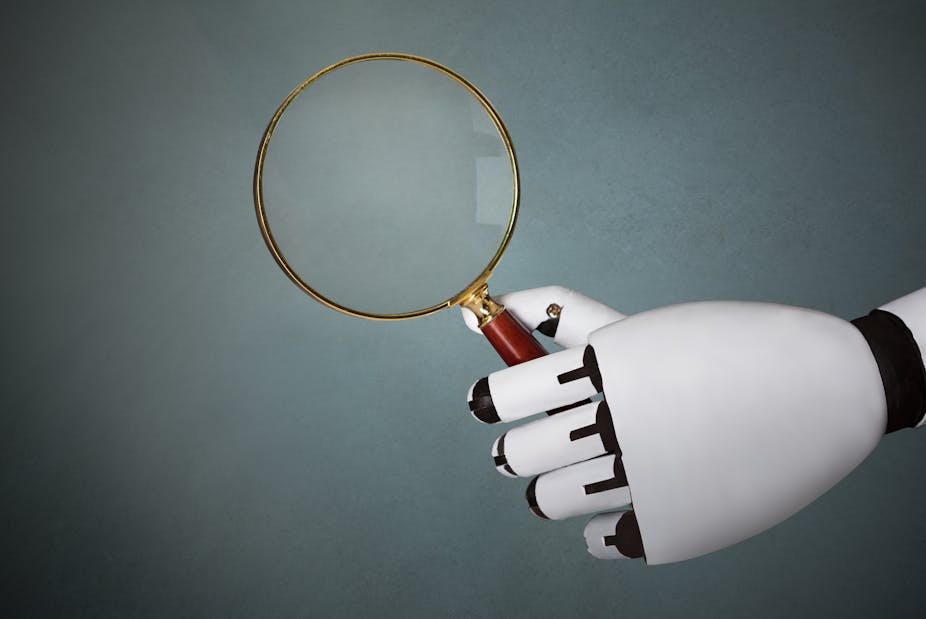 A robotic hand holds a magnifying glass.