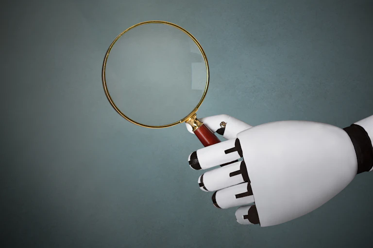 A robotic hand holds a magnifying glass.