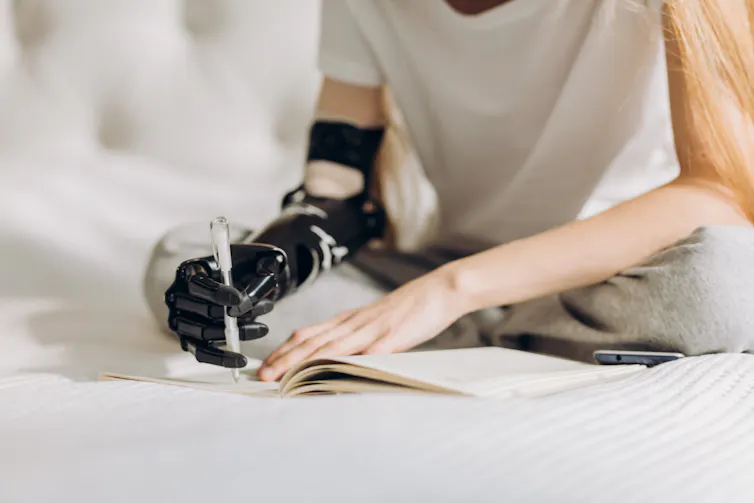 A person writing with a bionic arm.