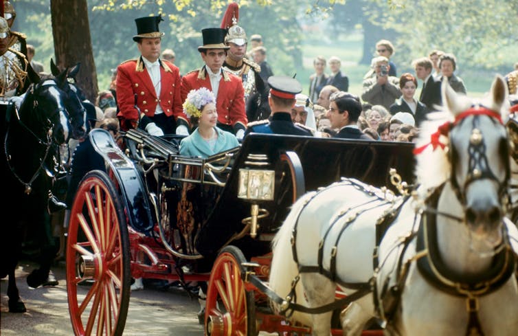 Queen Elizabeth II in a horse-driven carriage with the King Faisal of Saudi Arabia.