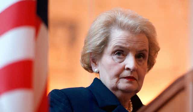 Madeleine Albright stands behind a United States flag.
