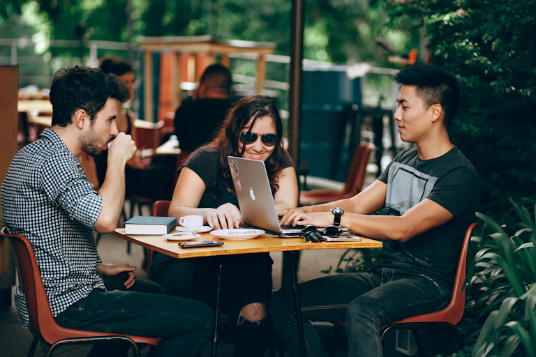 Three young people working at an outside table.