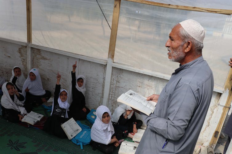 A man teaches a class of Afghan schoolgirls.