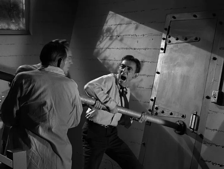 Man screams as he tries to ram open a door to a bomb shelter.