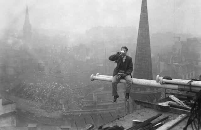 Man sitting on pole, drinking tea high above London.