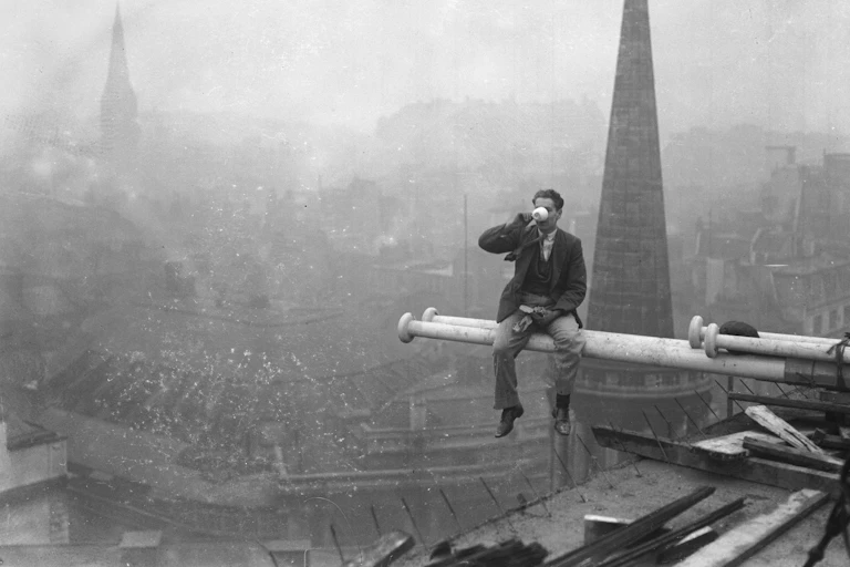 Man sitting on pole, drinking tea high above London.
