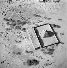 A black and white aerial photo of a square structure, some under roof but mostly an open courtyard with  a pyramid-like shrine in the centre.