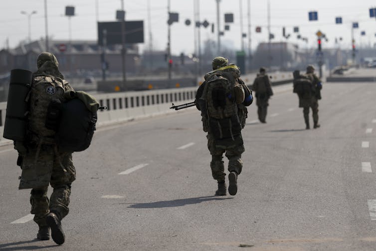 Soldiers cross a bridge in a city.