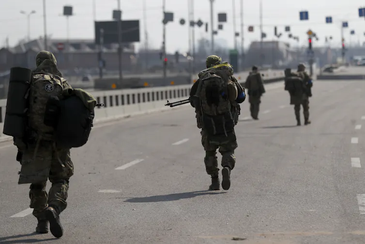 Soldiers cross a bridge in a city.