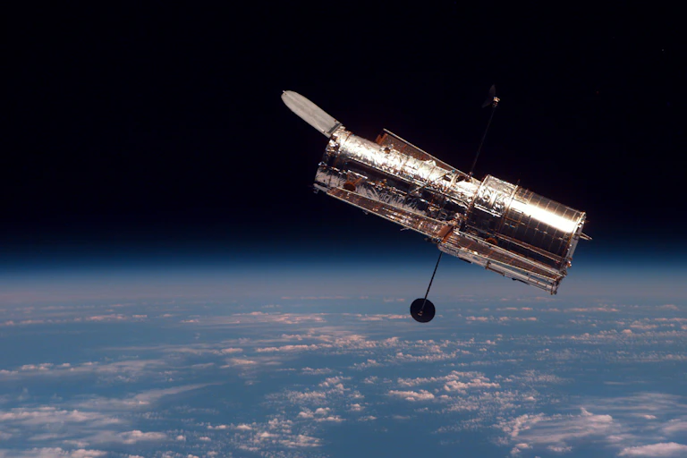 A shiny cylindrical telescope in orbit above Earth.