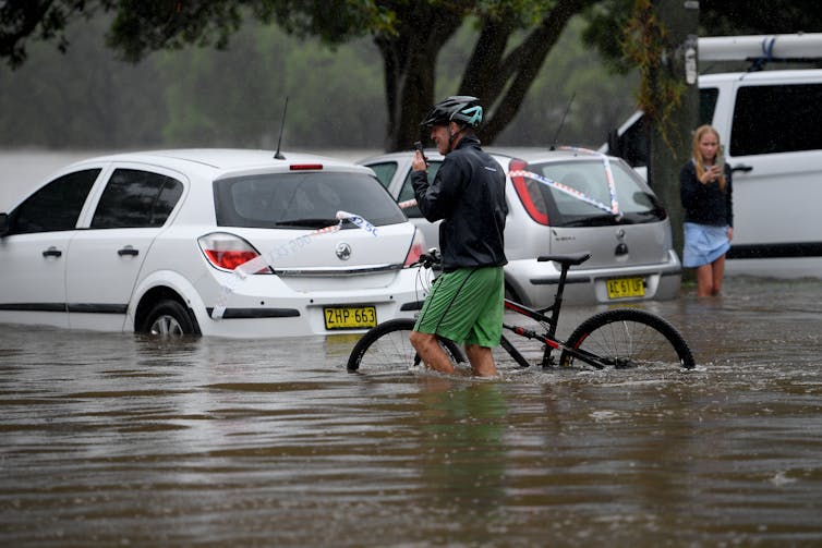 A man on a bike wades through floodwater