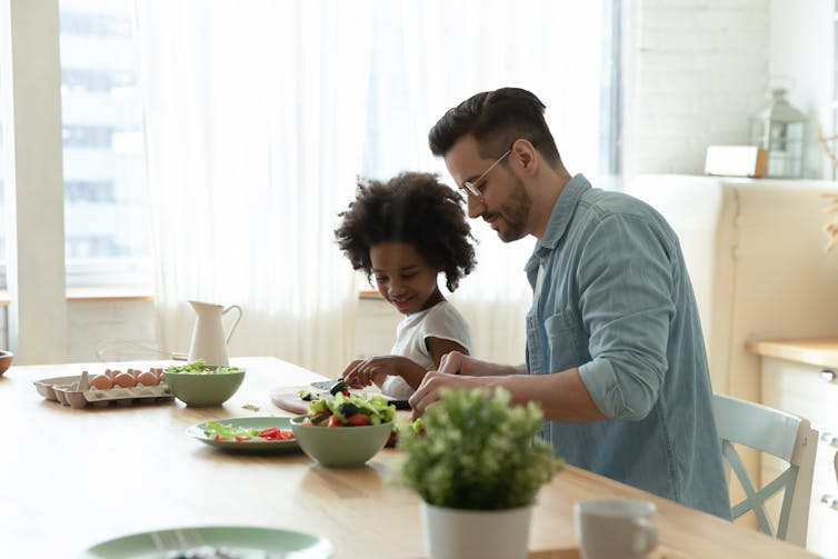 Father and child preparing a meal at the bench.